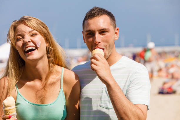 istock Man and woman eating ice cream on beach 1164003246