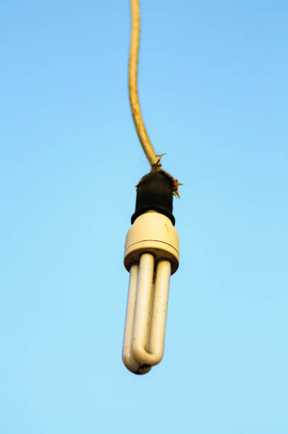 istock Uncovered low-energy light bulb hanging outside against a blue sky 1164004795