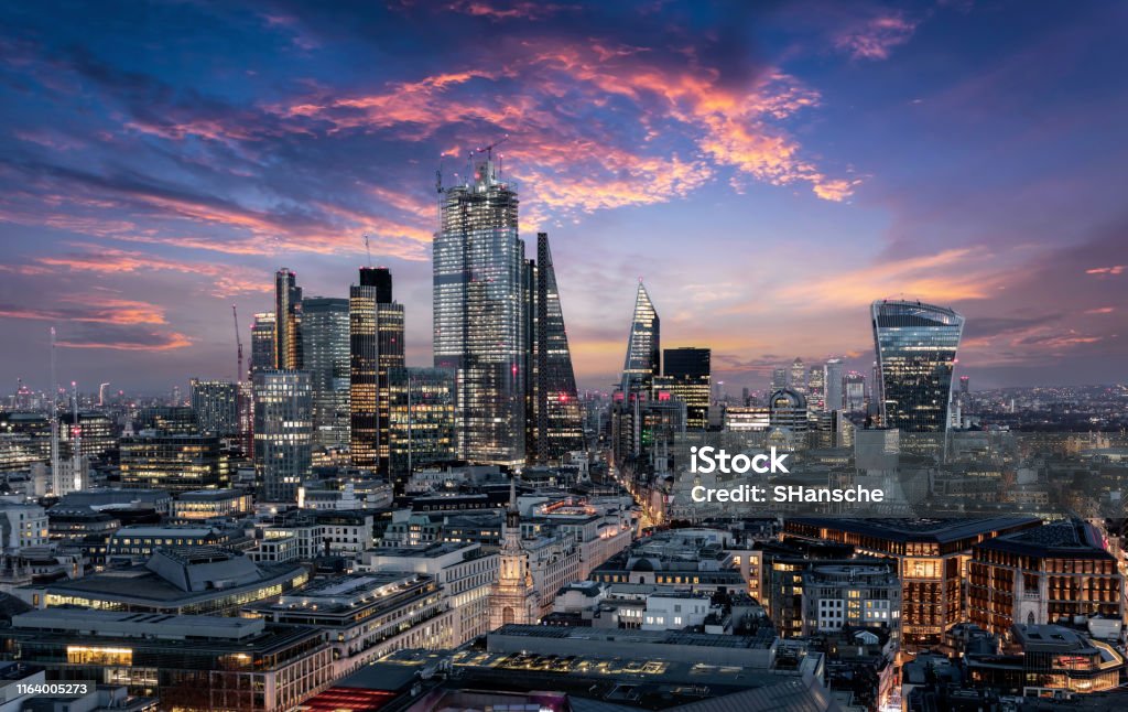 The City of London just after sunset, United Kingdom The City of London, financial district of the Metropole, just after sunset with illuminated buildings and cloudy sky, United Kingdom London - England Stock Photo