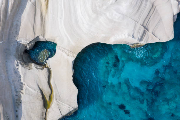 Aerial top down view to the chalk rock formations of Sarakiniko, Milos island, Cyclades, Greece Aerial top down view to the chalk rock formations of Sarakiniko with sparkling blue sea, Milos island, Cyclades, Greece aegean islands photos stock pictures, royalty-free photos & images