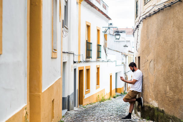 Casual man leaning on the wall holding his phone