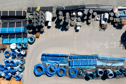 PVC plastic pipes for underground water supply and water meter covers viewed from above at a depot.