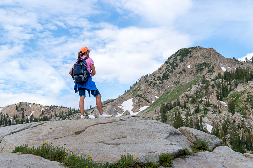 This shot was taken near Lake Mary during the summer.  Patches of snow can still be scene on the sides of the surrounding mountains.  The woman shown wearing a backback hiked up to the lake and is now admiring its beauty and the beauty of the surrounding mountains.