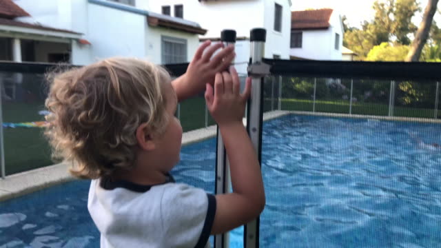 Child trying to open swimming pool safety fence
