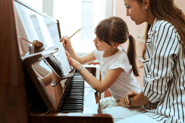 istock Young woman piano teacher educating child to write notes 1164013419