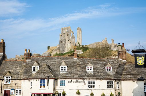 Corfe Castle, United Kingdom - February 13th, 2017 : A distant view of the castle ruins rom the town of Corfe Castle.  Corfe Castle is a village in the county of Dorset. It is the site of a ruined castle of the same name. The village and castle stand over a gap in the Purbeck Hills on the route between Wareham and Swanage.