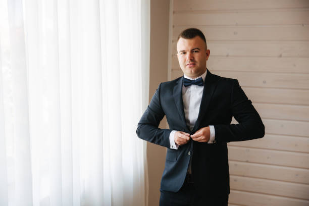 istock Young groom dressed in his home. Handsome man in wedding suit smile 1164014729