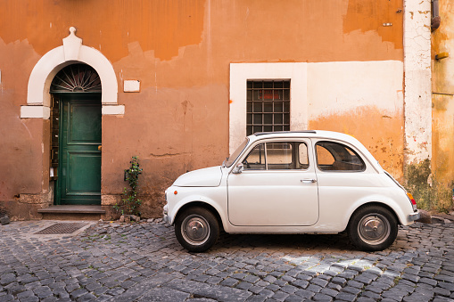 Vintage car parked in a cozy street in Trastevere, Rome, Italy, Europe.