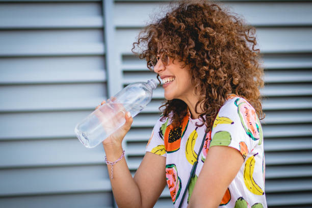 hydratatie tijdens de zomer. een jonge vrouw drinkt water - drinking water stockfoto's en -beelden