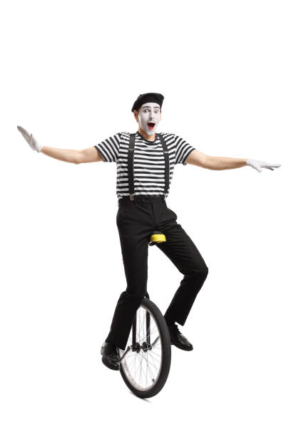 istock Mime riding a unicycle and balancing with hands 1164018579