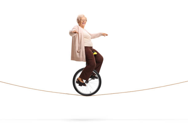 ロープに乗ってモノサイクルに乗り、カメラに微笑む高齢女性 - unicycle unicycling cycling wheel ストックフォトと画像