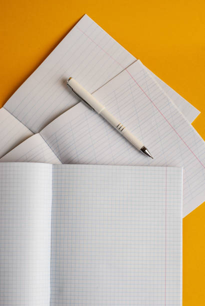 Open notebooks on a yellow background with a white pen, accessories for studying on a yellow background. With space for copy space. Minimalism. View from above