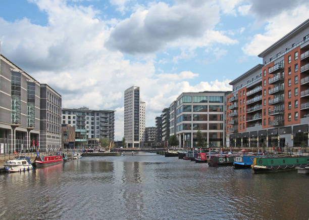 a view of of leeds dock with modern apartment developments and bars with moored houseboats and blue cloudy sky - leeds england yorkshire canal museum imagens e fotografias de stock