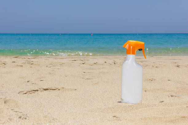 istock Bright white sunscreen spray on sand by turquoise water sea 1164023418