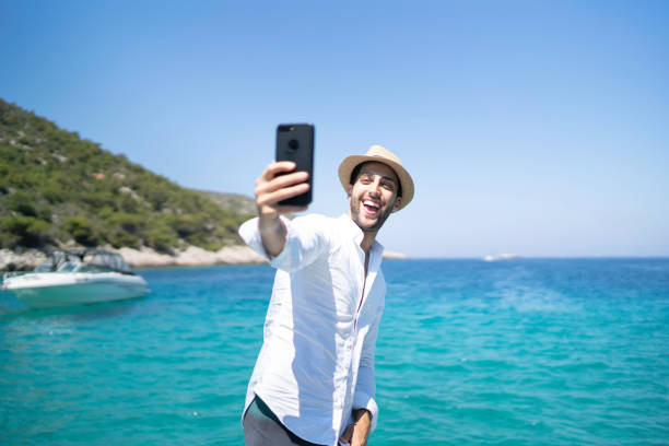 istock Happy young man taking a selfie at the beach 1164027424