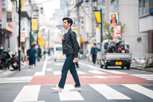 istock Young Japanese Man Walking in a Tokyo Zebra Crossing 1164033381