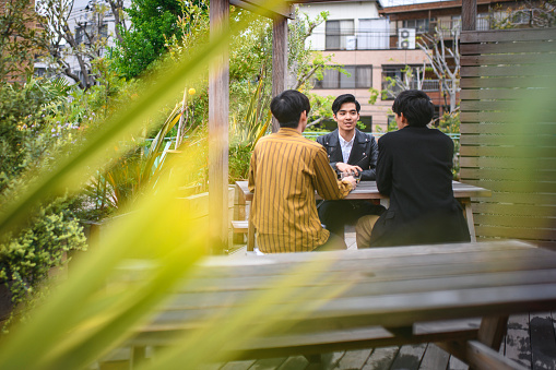 Three young and relaxed Japanese friends enjoying a day off and good conversation in a Tokyo rooftop garden.