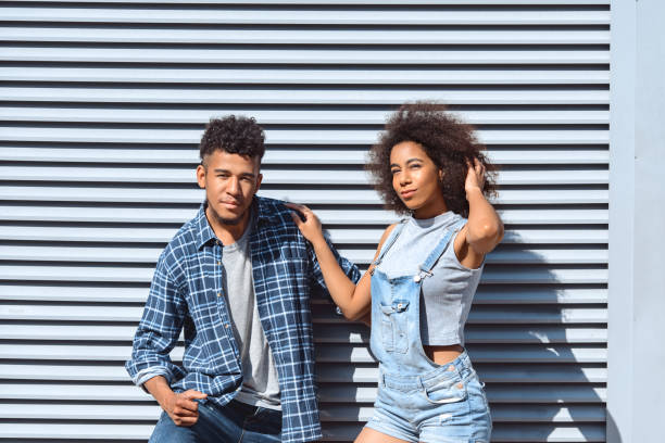 istock Young and Free. Couple standing isolated on wall hugging posing to camera confident 1164033425