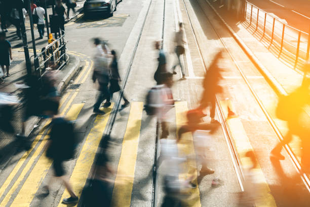 attraversamento pedonale a busy city con luce solare - defocused crowd blurred motion business foto e immagini stock