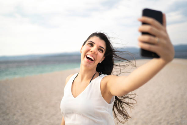 istock Happy young woman taking a selfie at the beach 1164034879