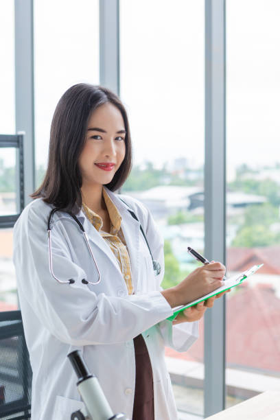笑顔のアジアの栄養士医師の女性が紙の緑色のボードに書く - genetic research chemist writing science ストックフォトと画像