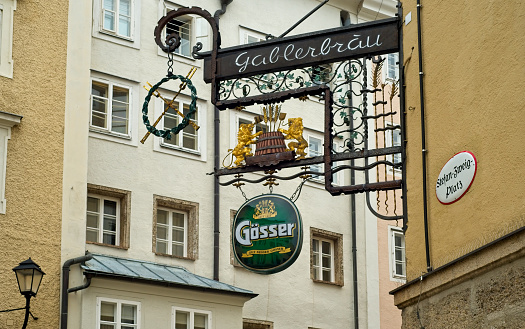 Salzburg, Austria - May 26, 2019: The ornate sign for the Gablerbräu restaurant hangs above the Stefan-Zweig Platz in a charming section of this beautiful city's old town.