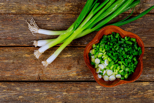 Scallion on wood background and cut green ono in wood plate