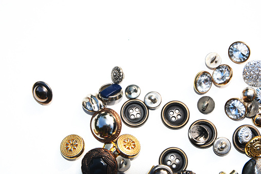 Metal sewing buttons of different sizes and shapes on an isolated background