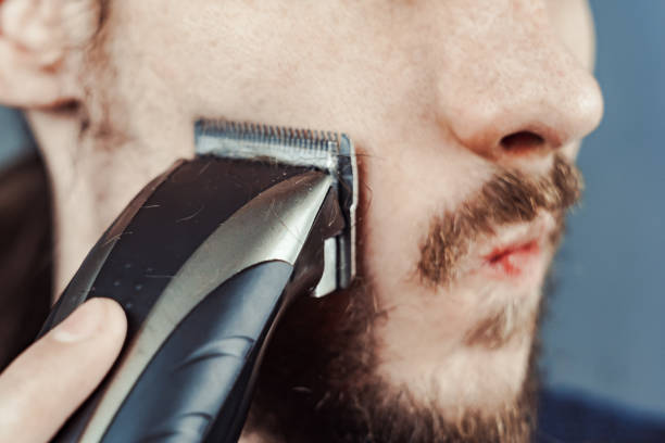 istock guy shaves his beard with an electric razor 1164056190