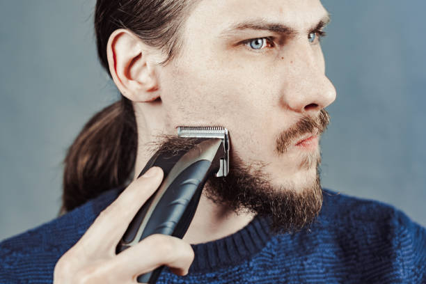 istock guy shaves his beard with an electric razor 1164056192
