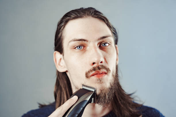 istock guy shaves his beard with an electric razor 1164056236