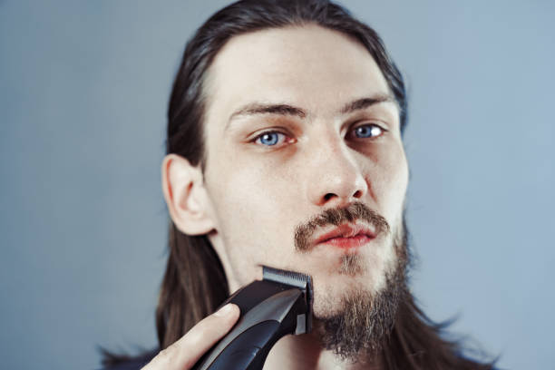 istock guy shaves his beard with an electric razor 1164056240