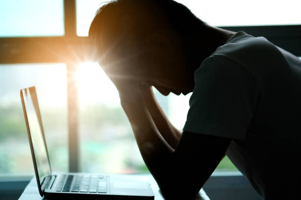 istock A man sitting down, his face unsettled. At the computer desk He has headaches and stress. Cause of hard work and insufficient rest. 1164056871