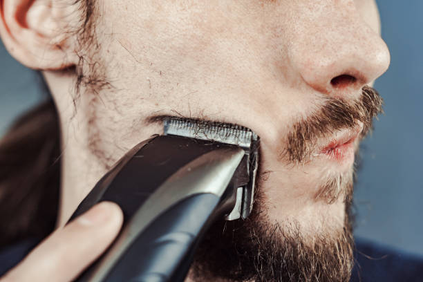 istock guy shaves his beard with an electric razor 1164056875