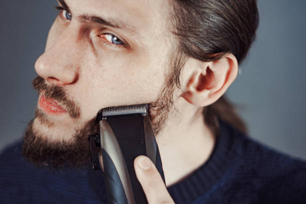 istock guy shaves his beard with an electric razor 1164056902