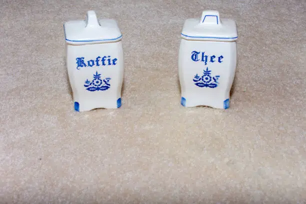 Photo of Delft Blue Coffee and Tea (Koffie and Thee) containers. Famous porcelain souvenirs from Holland/Netherlands. Isolated on textured beige background.