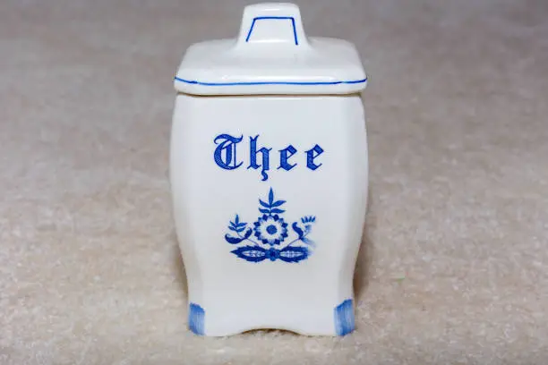 Photo of Delft Blue Tea (thee) container. Famous porcelain souvenirs from Holland/Netherlands. Isolated on textured beige background.