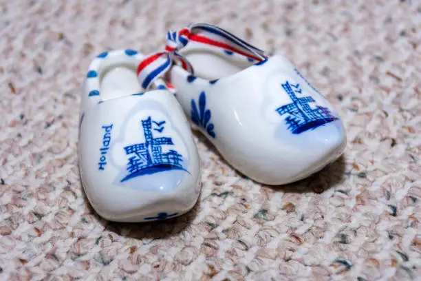 Photo of Delft Blue Figurine of dutch wooden shoes porcelain. Souvenir from Holland/Netherlands. Isolated on textured beige background.