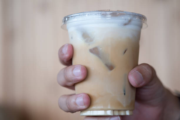 istock Hand hold iced coffee with cream poured over 1164064922