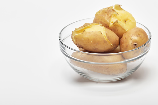 Boiled potatoes in a glass bowl on white background