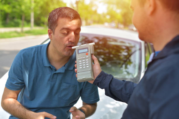 Driver due to being subject to test for alcohol content with use of breathalyzer Driver due to being subject to test for alcohol content with use of breathalyzer sobriety stock pictures, royalty-free photos & images