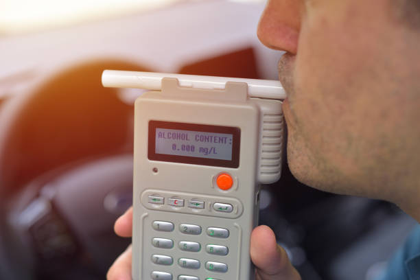 conductor debido a estar sujeto a pruebas de contenido de alcohol con el uso de alcoholímetro - aliento fotografías e imágenes de stock