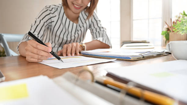 secrétaire femme analyse des données financières sur papier avec un stylo. - bureaucracy photos et images de collection