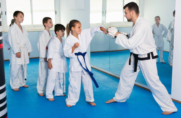 istock Children training karate kicks on punching bag during karate class 1164076194