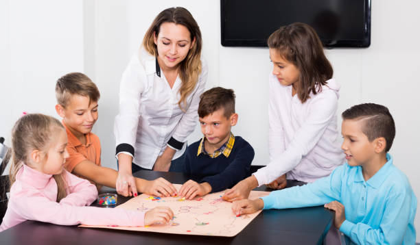 istock Happy children sitting at table with board game 1164076490