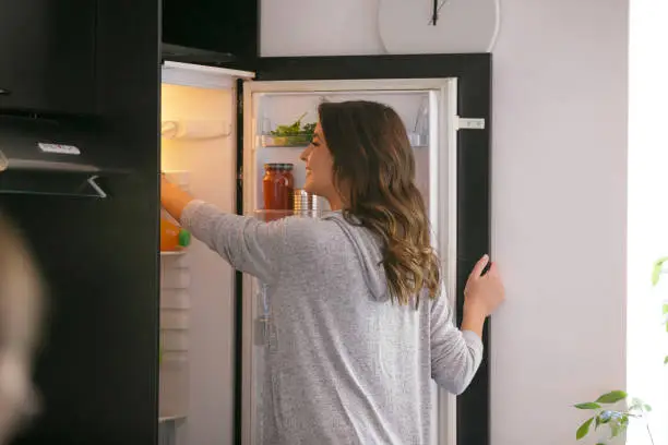 Photo of Happy woman taking food from the fridge