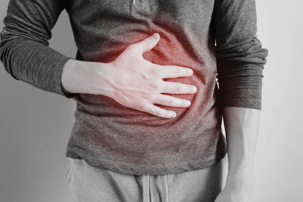Man holding his sore belly A man holds the stomach. The pain in his chest. Heartburn. Stomach hurts. Sore point highlighted in red. Closeup. Isolated gastroenteritis stock pictures, royalty-free photos & images
