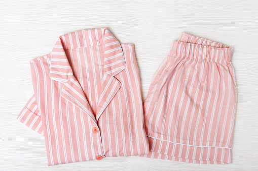 Pink pajamas on white wooden surface. Night suit for sleeping. Copy space. Top view. Flat lay.