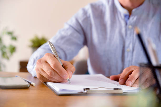 istock Man filling out a questionnaire on a wooden table front 1164086919