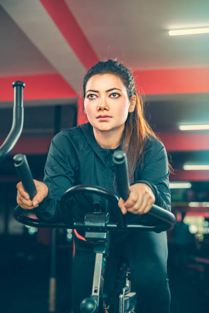 Beautiful woman does cardio exercise on air bike in gymnasium. stock photo